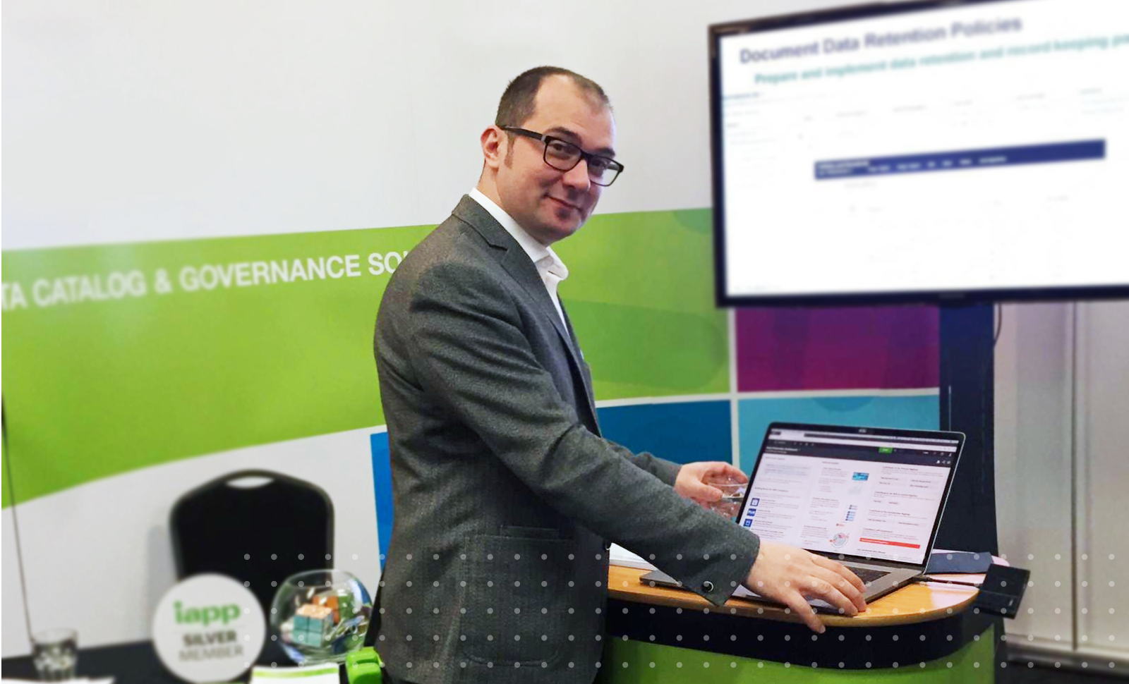 Collibra sales engineer senior manager Tudor Borlea stands at a computer in a Collibra-branded event booth