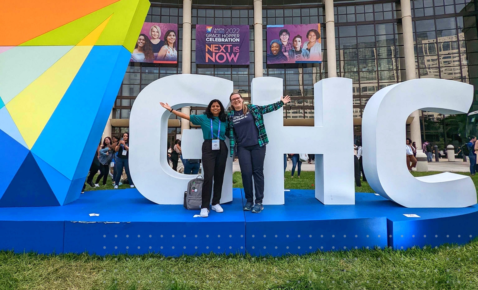 Vidhya Sitaraman, a Senior Software Engineer, and Karina Galinskaya, a Business Intelligence Analyst, stand together outside the Grace Hopper Celebration