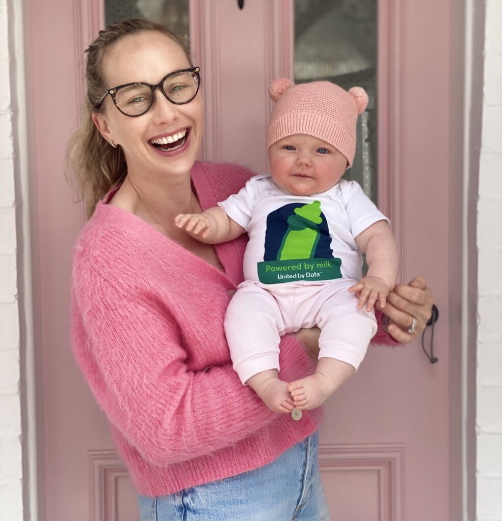 Lucy Whitty holds her infant daughter, who is wearing a Collibra-branded onesie
